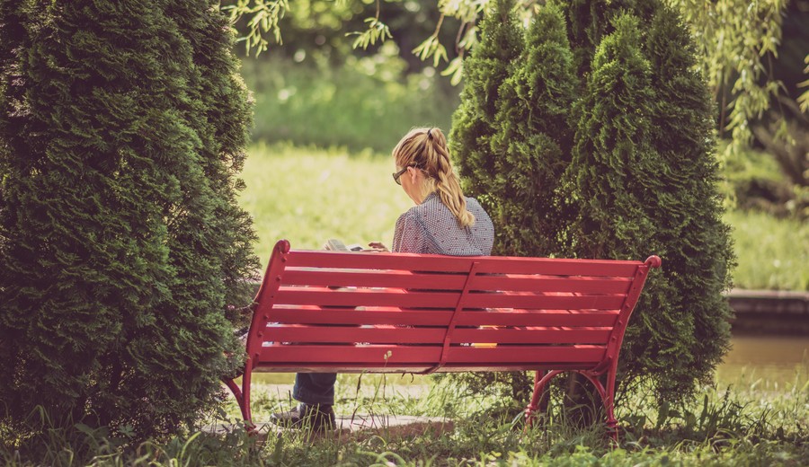 Lady sitting on a bench, reading a book